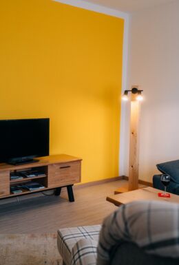 Innenaufnahme Wohnzimmer mit Sessel, Sofa und TV-Bank