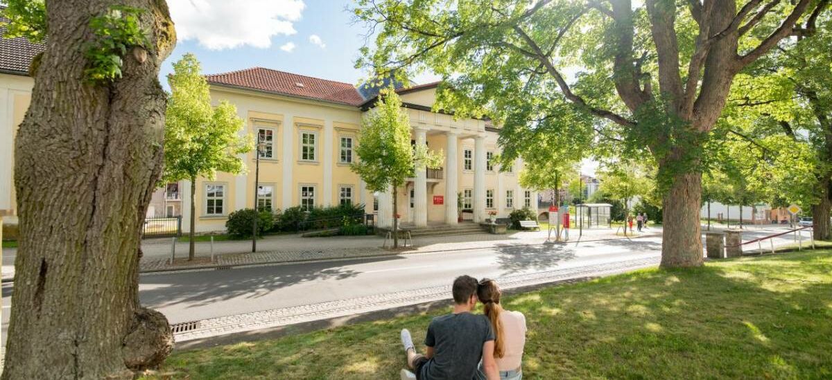 Landschaftsaufnahme mit Pärchen auf Wiese, im Hintergrund Palais Weimar mit Stadt- und Kurbibliothek